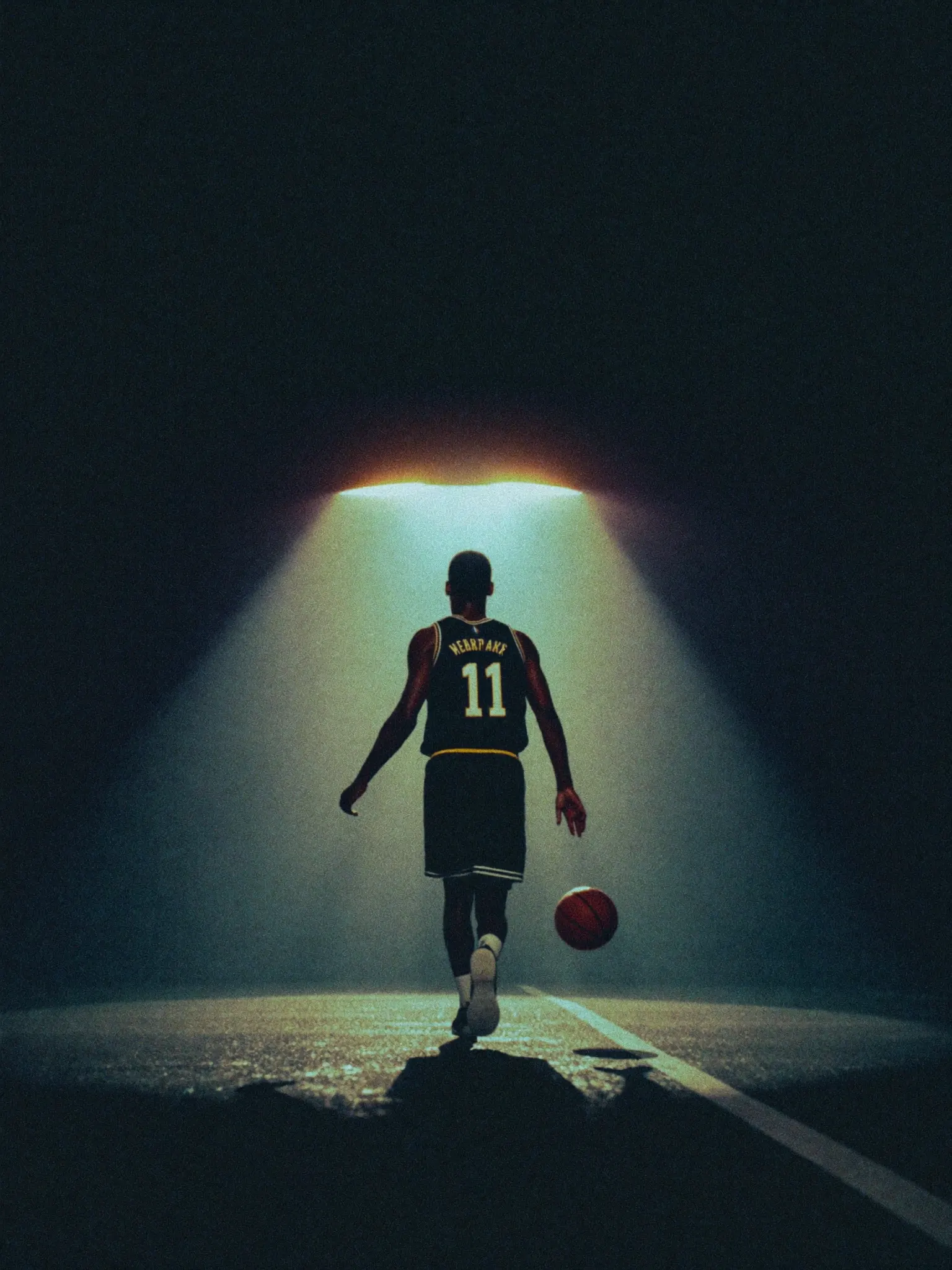 A basketball player walking toward the light of a stadium tunnel
